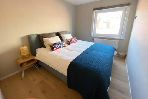 ein Schlafzimmer mit einem großen Bett mit Kissen und einem Fenster in der Unterkunft modern appartement near beach in Knokke in Knokke-Heist