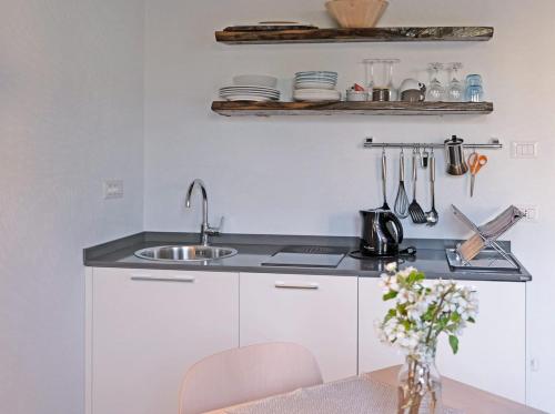 eine weiße Küche mit einem Waschbecken und einem Tisch in der Unterkunft Casa Visette in Monforte dʼAlba