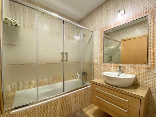 a bathroom with a sink and a shower and a mirror at Varandas - Arrifana, com piscina, junto à praia in Praia da Arrifana