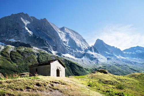 an old building on a hill in front of a mountain at Club Alpina - Champagny-en-Vanoise in Champagny-en-Vanoise