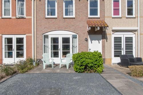 a brick house with white chairs and a patio at Middensluis Vakantiehuis in Wemeldinge