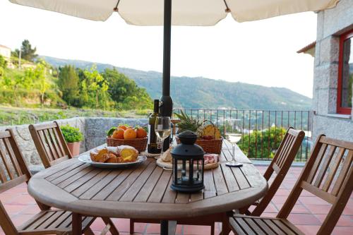 a wooden table with a bowl of fruit and an umbrella at Peso Village in Amarante
