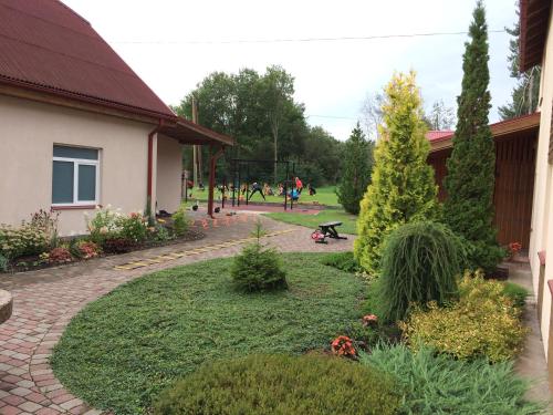 a garden outside a building with people in the background at Viesu nams Zivtiņi in Kaltene