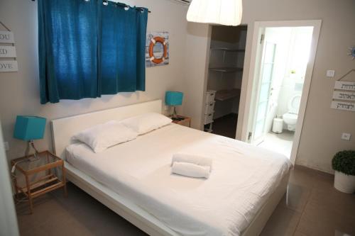a bedroom with a white bed with a blue curtain at Villa Sea House in Eilat