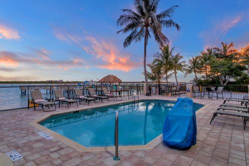 - une piscine dans un complexe avec des chaises et des palmiers dans l'établissement Hutchinson Island Hotel, à Fort Pierce