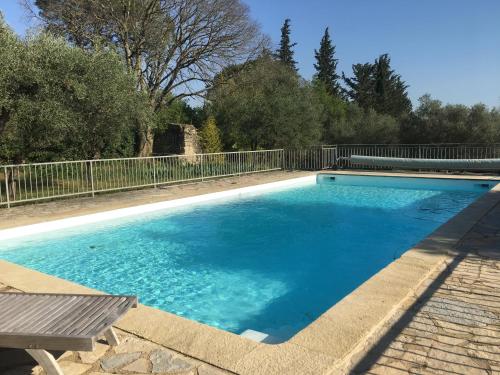 une piscine avec de l'eau bleue dans une cour dans l'établissement Les Olivettes le mazet, à Uzès