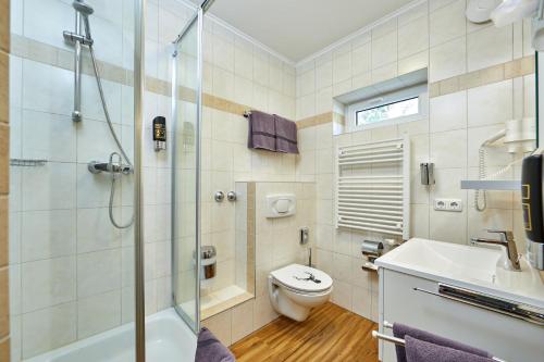 a bathroom with a shower and a toilet and a sink at Gästehaus Buchenhof in Grainau
