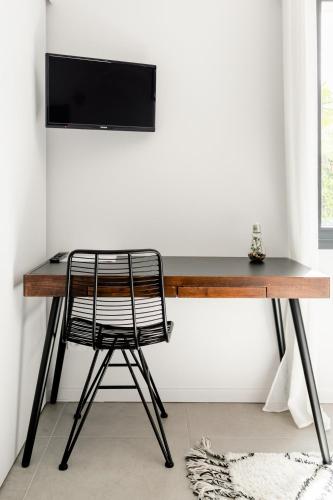 a desk with a chair and a television on a wall at Villa Géna in Saint-Médard-dʼEyrans