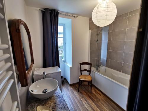 a bathroom with a toilet and a tub and a chair at Le Monrepos avec jacuzzi nordique in Bielle