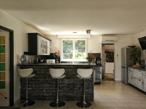a kitchen with a bar with white stools at La Petite Source in Montendre