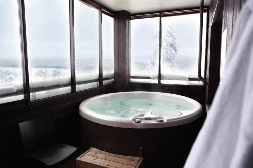 a bath tub in a room with windows at Ski-Inn RukaVillage in Ruka