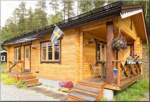 a small wooden cabin with a flag on it at Funäsdalens Stugby in Funäsdalen