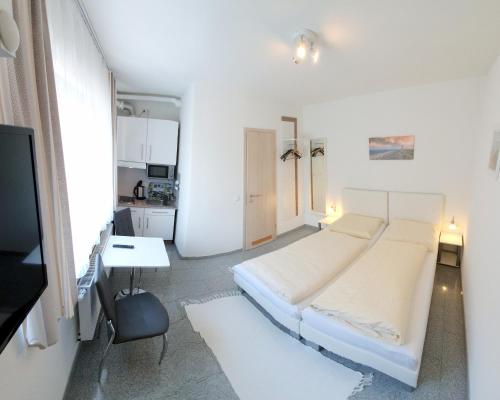 a white bedroom with a bed and a desk at Haus zum Schlosspark in Veitshöchheim