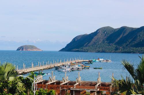 a dock with boats in the water next to mountains at Minh Minh Homestay in Con Dao