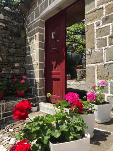 a red door with flowers in front of a building at The Mosaic House - Shtepia me Mozaik in Përmet