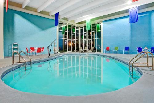 a pool in a hotel room with chairs and tables at Travelodge by Wyndham Iowa City in Iowa City