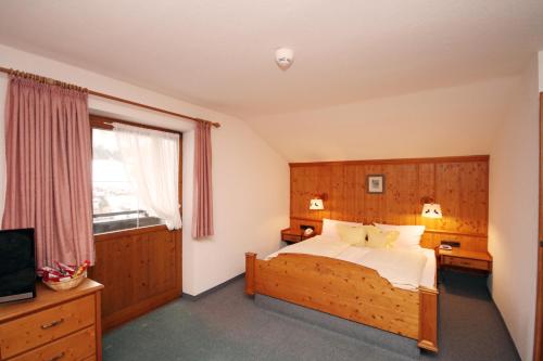a bedroom with a bed and a large window at Hotel Alpensonne in Riezlern