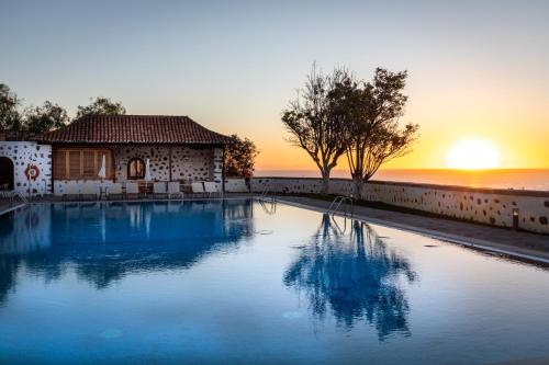 a swimming pool in front of a house with the sunset at Parador de La Gomera in San Sebastián de la Gomera
