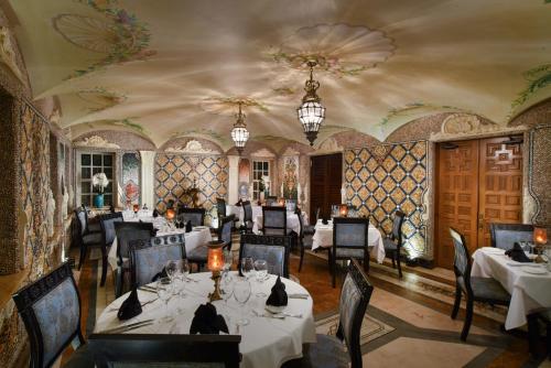 a restaurant with white tables and chairs and a ceiling at The Villa Casa Casuarina in Miami Beach