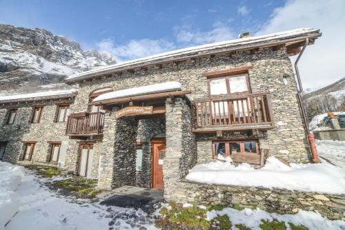 a stone house with a balcony in the snow at Chalet Della Guida in Bardonecchia