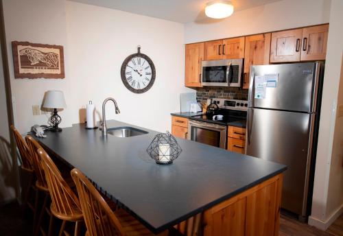 una cucina con piano di lavoro nero e frigorifero in acciaio inossidabile di Mountain Lodge at Okemo-1Br Fireplace & Updated Kitchen condo a Ludlow