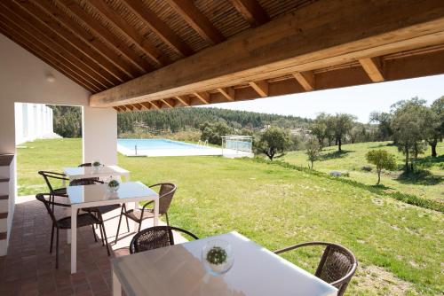 a patio with tables and chairs and a view of a yard at Monte das Texugueiras - Adults Only in Texugueira