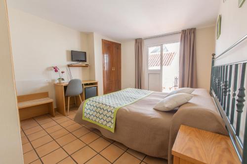 um quarto com uma cama, uma secretária e uma janela em Hostal El Gallo em Marbella