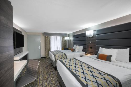 a hotel room with two beds and a flat screen tv at Baymont by Wyndham Murfreesboro in Murfreesboro