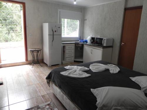 Il comprend une chambre avec un lit et une cuisine équipée d'un réfrigérateur. dans l'établissement V do Lago Negro, à Gramado