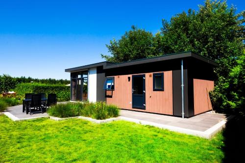 een kleine hut met een zwart dak op een gazon bij Waadhoeke - Resort in Menaldum