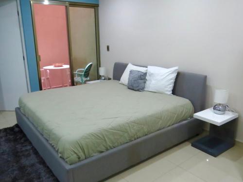 a bedroom with a large bed with a side table at Palmarena Rooms & Residences - Long Stay Comfort with Parking, Sauna, Gym & Pool - Steps from 5th Avenue in Playa del Carmen