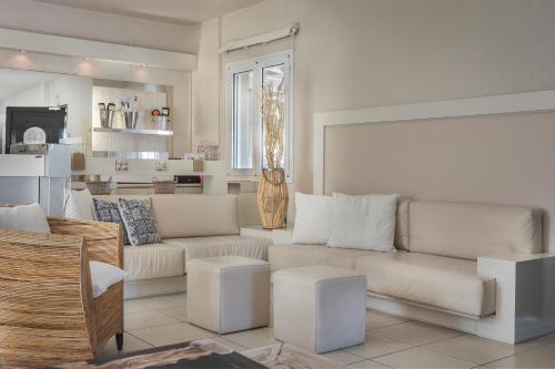 a living room with white couches and a kitchen at Captain's House Hotel in Skala Kefalonias