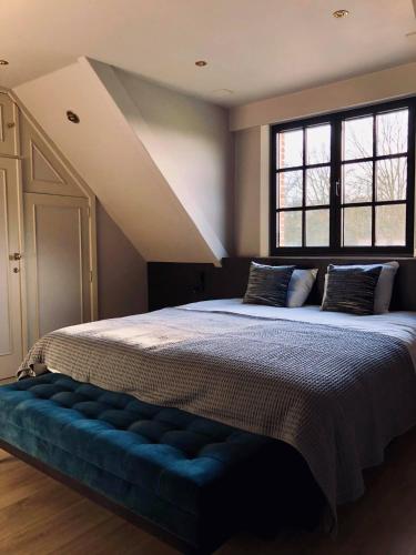 a bedroom with a large bed with a blue bench at 't Averhuys in Itegem