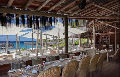 a restaurant with tables and chairs and a view of the ocean at Canouan Estate Resort & Villas in Canouan