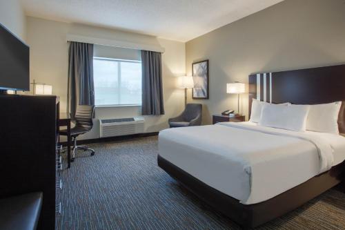 a hotel room with a large bed and a desk at Wingate by Wyndham Gurnee in Gurnee