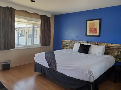 a bedroom with a large bed with a blue wall at PineCrest Inn & Suites in Flagstaff