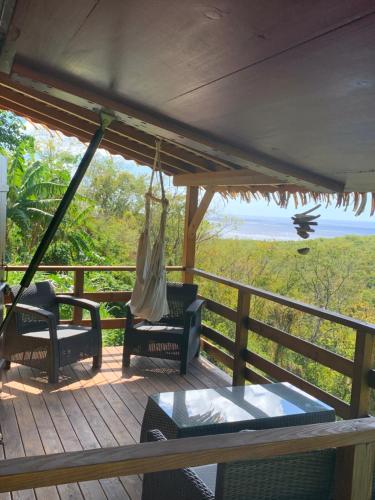 een veranda met stoelen en een hangmat en de oceaan bij Domaine Karaibes in Deshaies
