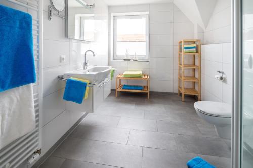 a white bathroom with a sink and a toilet at Haus an den Dünen in Norderney