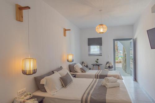 two beds in a white room with two lamps at Fragoulis Village in Parasporos