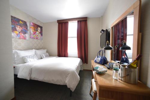 Cette chambre comprend un lit, un bureau et une fenêtre. dans l'établissement Hotel Mimosa, à New York