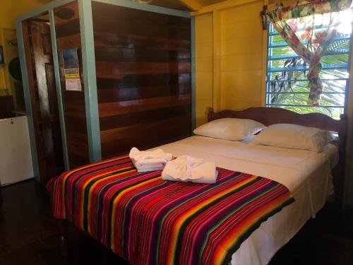 a white bed sitting in a bedroom next to a window at Colinda Cabanas in Caye Caulker