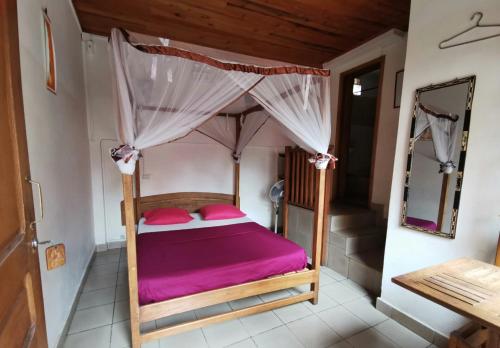 a bedroom with a canopy bed with pink sheets at Hotel St-Antoine in Antananarivo