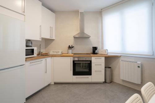 a kitchen with white cabinets and a stove top oven at Bilbao High Apartment in Bilbao
