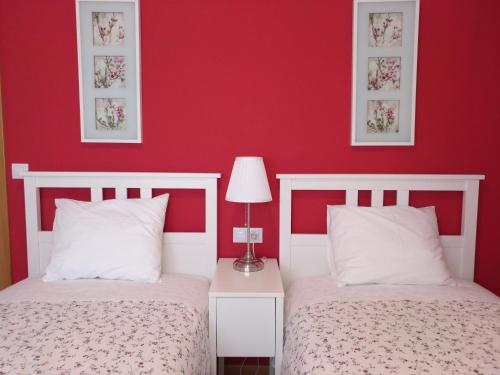 two beds in a bedroom with red walls at Apartamento Turistico Cigüeña de Arguedas in Arguedas