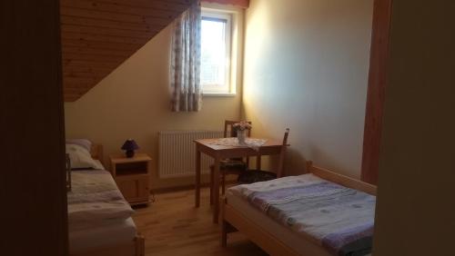 Zimmer mit 2 Betten, einem Tisch und einem Fenster in der Unterkunft Rekreačné zariadenie Chmelisko in Pružina