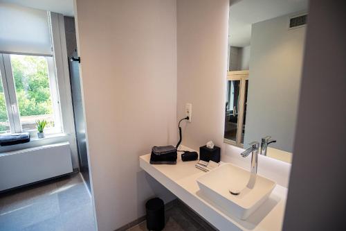 a white bathroom with a sink and a mirror at Burgemeesterhuys in Beringen