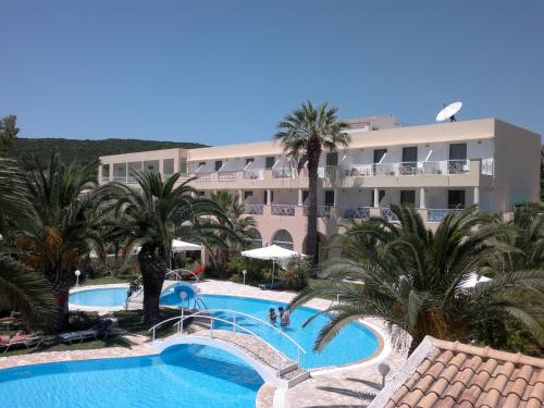 a resort with a swimming pool with palm trees and a building at Three Stars Beach Hotel in Moraitika