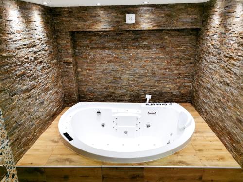 a bath tub in a room with a brick wall at Canti apartments in Novi Sad