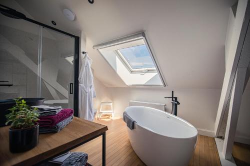 a bathroom with a large white tub and a skylight at Boetiekhotel Burgemeesterhuys in Beringen