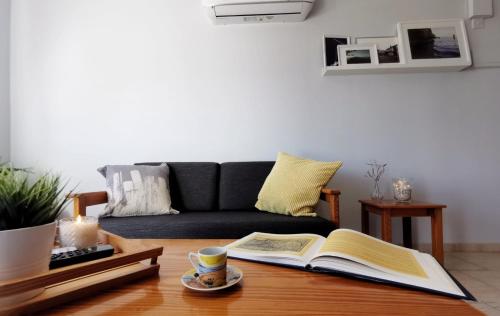 a living room with a couch and a coffee table with an open book at Anemomylos guesthouse in Paralimni